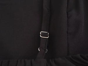 Detailed macro view of adjustable shoulder strap with silver metal buckle on black dress
