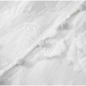 Détail de broderie florale blanche et boutons recouverts sur une robe avec col en V chic