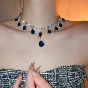 Detail of silver choker necklace featuring deep blue teardrop gems and crystal pavé accents