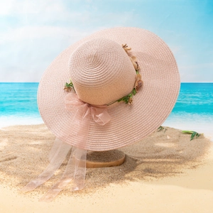 Close-up of wide brim straw sun hat with floral decoration and pink organza ribbon