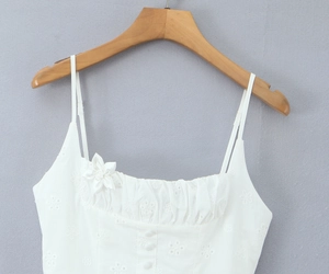 Detail of white dress with hollow-out embroidery, 3D flowers, and decorative buttons