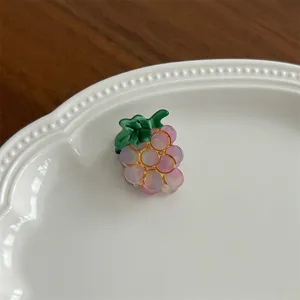 Macro view of a purple resin grape hair clip featuring a gradient finish on a ceramic plate