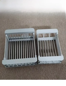 Close-up of adjustable stainless steel sink rack showing telescopic bars and grey ends