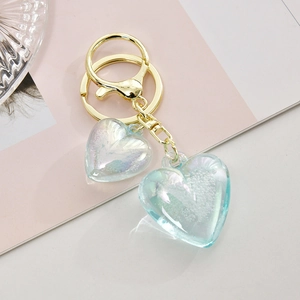 Detailed macro of golden metal keychain with dual translucent iridescent heart pendants