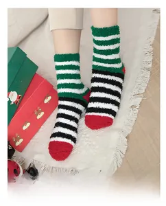 Close-up of festive striped coral fleece socks in red and green on a white rug