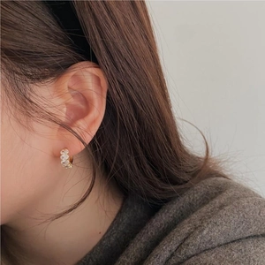Close-up of gold mini hoop earring with sparkling oval cubic zirconia on woman's ear