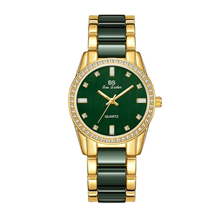 Macro detail of luxury gold and green quartz watch featuring rhinestone-set dial and bezel