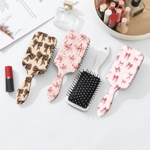 Pastel hairbrushes with cute bow and lipstick patterns on a minimalist white desk