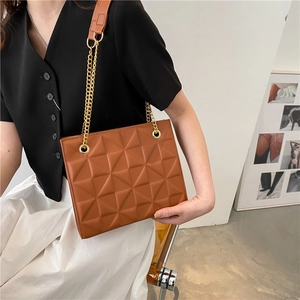 Close-up of brown quilted shoulder bag with gold chain strap and diamond pattern