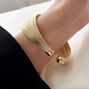 Detail of gold layered wrap cuff bracelet with polished spherical ends on wrist