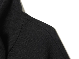 Close-up of black wool houndstooth jacket showing twill texture and shoulder seam detail