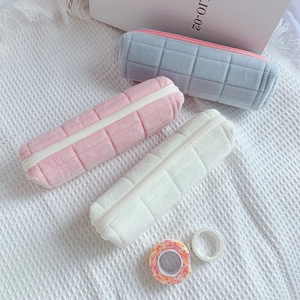 Detailed top view of soft velvet pencil cases in blue, pink, and beige with grid texture
