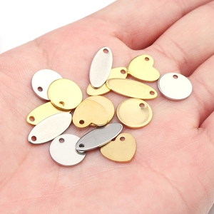 Macro shot of gold and silver heart and oval metal charms held in hand for scale