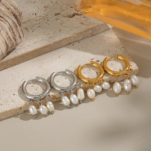 Détail de boucles d'oreilles en perles dorées et argentées sur une dalle avec coquillages