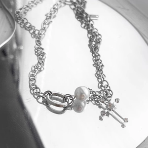 Detail of silver double-layered chain necklace with pearl and rhinestone cross pendant