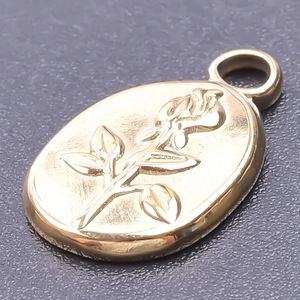 Macro detail of oval gold floral pendant with embossed rose and polished 18k finish