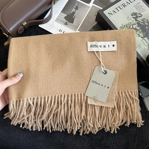 Close-up of solid camel cashmere feel scarf with tassel detail and minimalist label