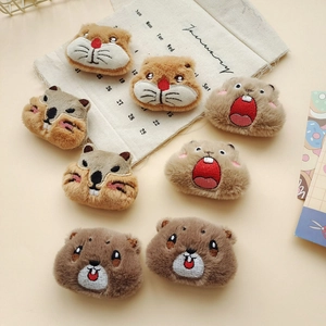 Vista dettagliata di vari distintivi in peluche a forma di marmotta e criceto in toni beige