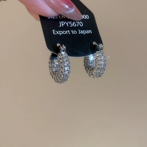 Detail of silver U-shaped hoop earrings with sparkling cubic zirconia on a black display tag