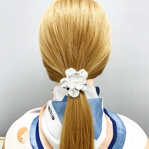 Detailed close-up of a silver alloy floral hair tie on a minimalist low ponytail style