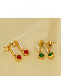 Detail of 18K gold-plated earrings featuring white pearls and green emerald-style gemstones