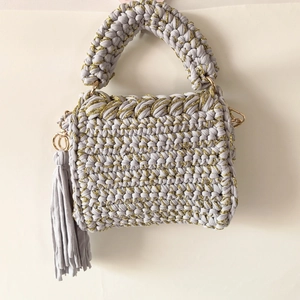 Detail of grey handmade crochet crossbody bag with gold thread weaving and tassel accessory