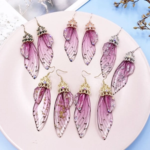 Detailed macro view of purple gradient cicada wing earrings with sparkling rhinestones