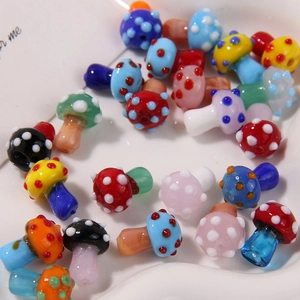 Macro view of colorful spotted glass mushroom beads for DIY jewelry in a white tray