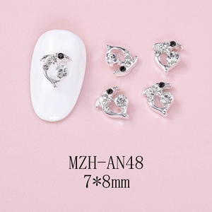 Macro shot of silver alloy dolphin nail charms with rhinestones on pink background