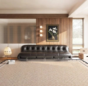 Detail of vintage French leather sofa with pleated texture on a large beige woven rug