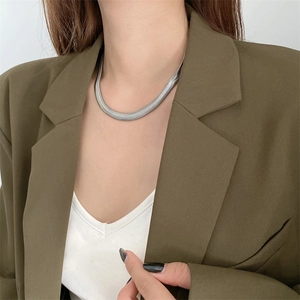Minimalist silver snake bone titanium necklace worn by a model with a green blazer