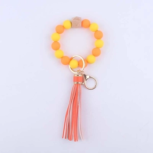 Detail of yellow silicone beaded keychain with wooden octagon bead and orange striped tassel