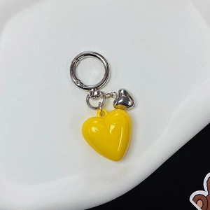 Detailed view of yellow resin heart keychain with silver ring on a white plate