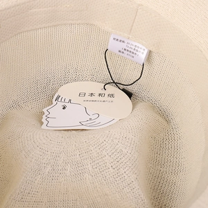 Close-up of beige woven sun hat with wash label and Japanese washi paper tag