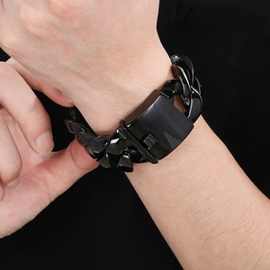 Detail of chunky black polished cuban link chain bracelet with mechanical clasp on wrist