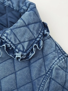 Close-up of blue quilted denim jacket with diamond patterns and ruffle trim details
