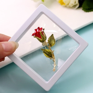Macro shot of red enamel rose brooch in clear PE film floating jewelry display box