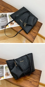Close-up of black V-quilted faux leather tote bag set with golden logo on wooden bench