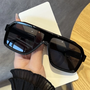 Detail view of large square black sunglasses with polished frames and dark tinted lenses