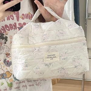Detailansicht der gesteppten Kosmetiktasche mit Blumenmuster und gewebtem Etikett