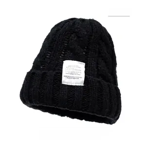 Detailed close-up of chunky knit texture and fashion label on a black winter beanie