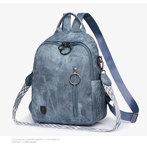 Detail of gray-blue leather backpack showing metallic ring zipper and woven shoulder strap