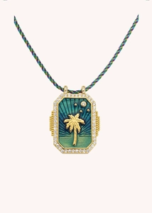 Detail of a gold tarot card necklace with palm tree motif and braided cord