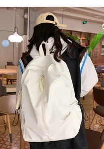 Detail of white nylon backpack featuring water-resistant fabric and side storage pocket