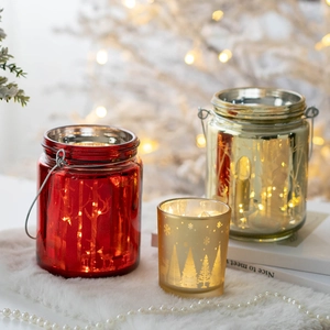 Christmas glass candle holder with reindeer etching and gold finish on plush surface