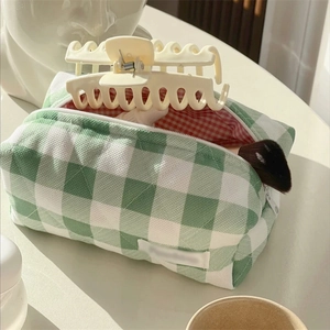 Detailed view of green checkered cotton makeup bag with brushes and hair accessories