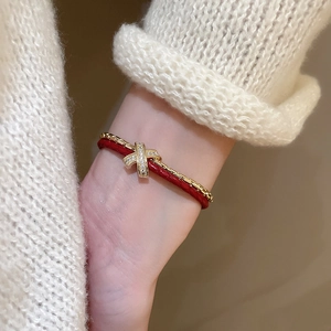 Détail du bracelet en cordon rouge et chaîne dorée avec un élément en cristal brillant