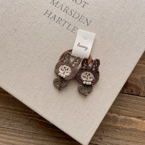Detail of handcrafted brown crochet bunny hair ties with pearls on a display card
