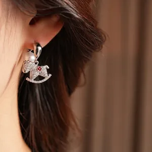 Elegant rocking horse stud earrings with sparkling rhinestones and white round pearls