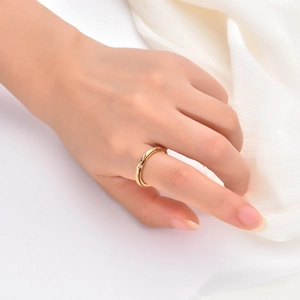 Detail of gold layered crossover spinning ring worn on hand with silk background
